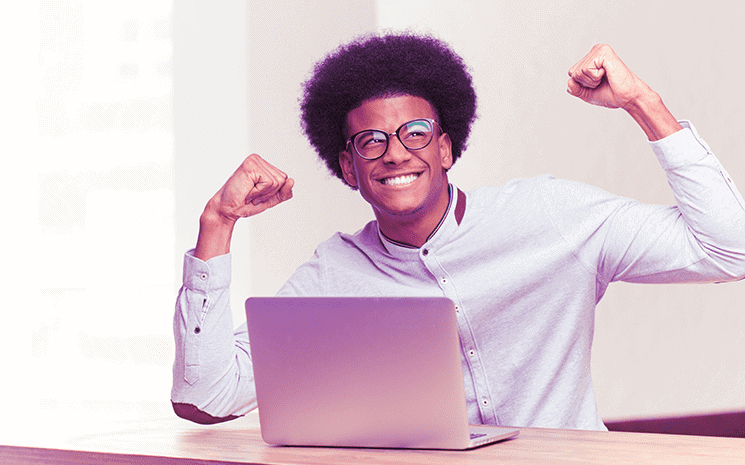 Jovem negro na frente do computador comemorando sua entrada no programa de startups
