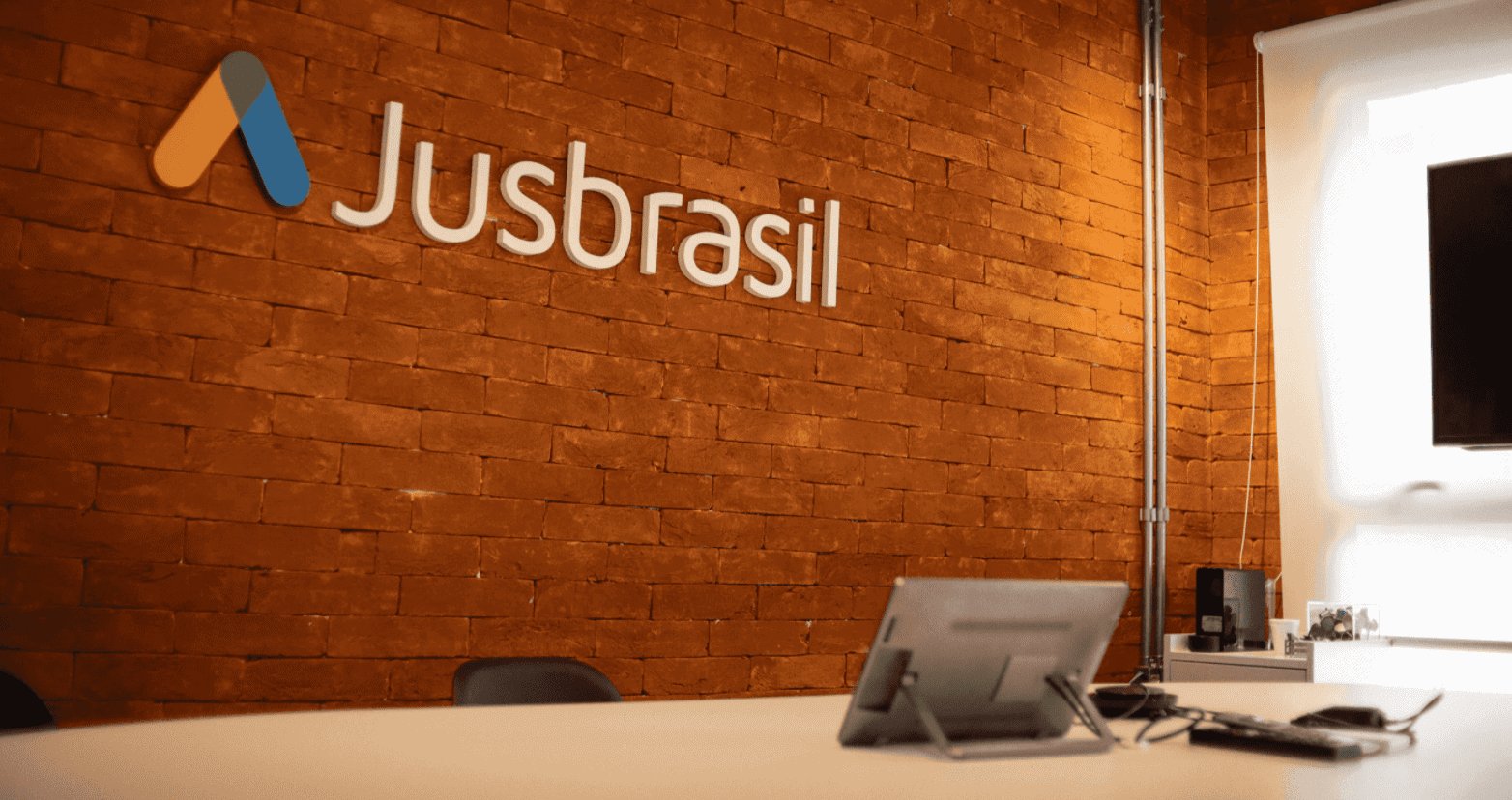 Na imagem, você vê uma foto da uma parada com a fachada e logo do jusbrasil, startup jurídica brasileira, que levantou mais de US$ 30 milhões em reodada Series C