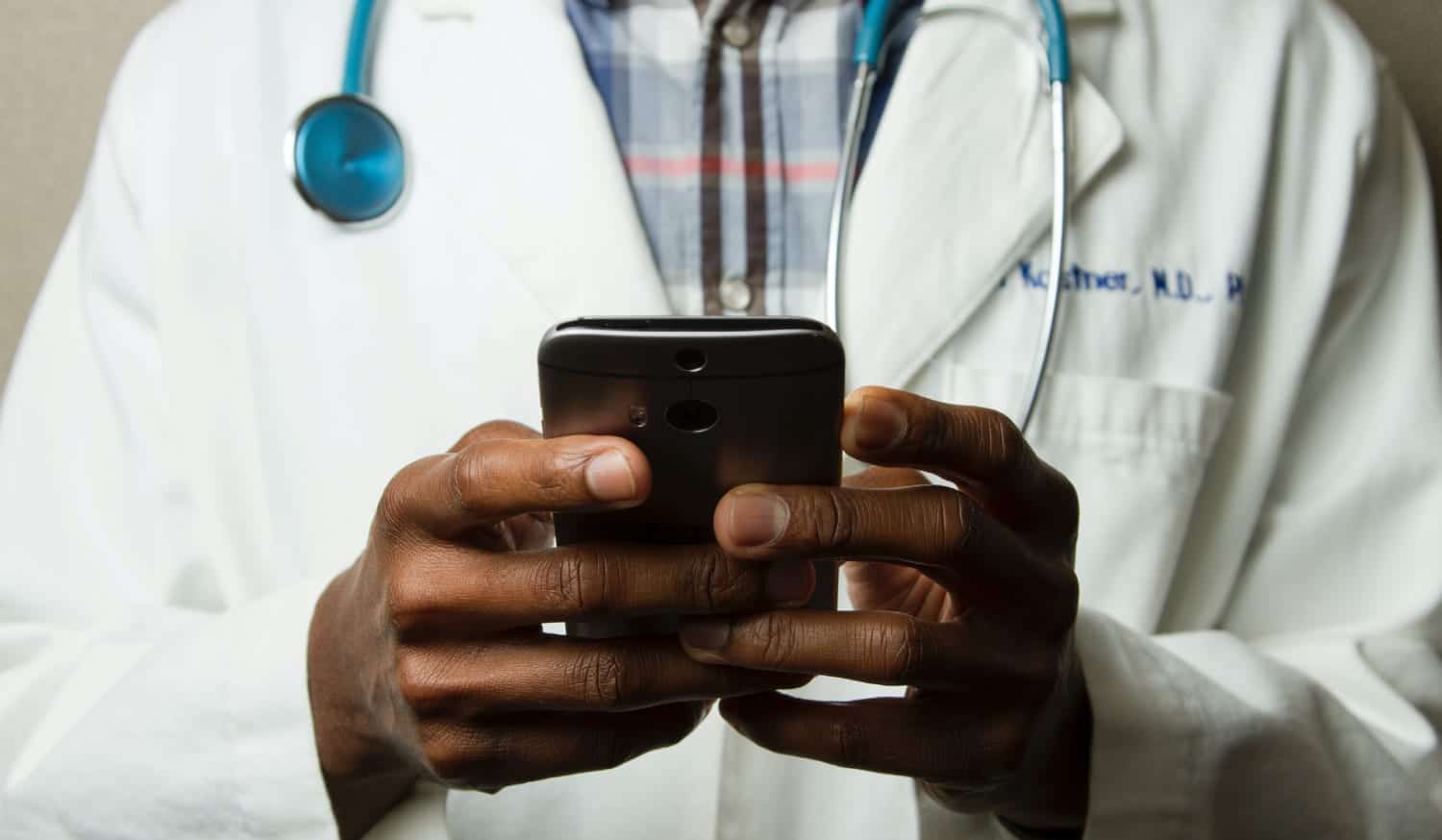 Médico com celular na mão pesquisa sobre jornada digital do paciente