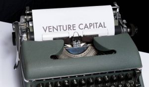A imagem mostra uma máquina de escrever com uma folha de papel em que se lê 'venture capital'